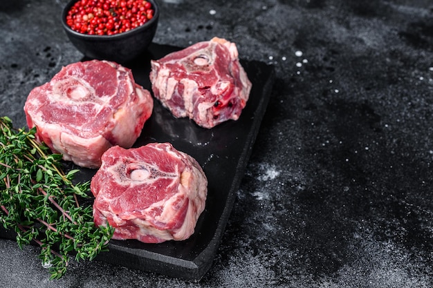 Rohes Lammhalsfleisch auf einem Marmorbrett. Schwarzer Hintergrund. Ansicht von oben. Platz kopieren.