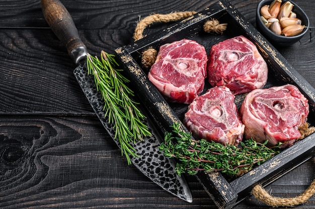 Rohes Lammhalsfleisch auf einem Metzgertisch mit Messer. Schwarzer hölzerner Hintergrund. Ansicht von oben. Platz kopieren.