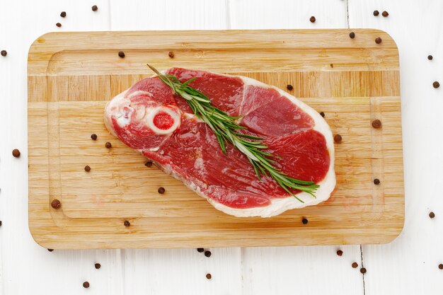 Foto rohes lammsteak an bord auf weißem holztisch