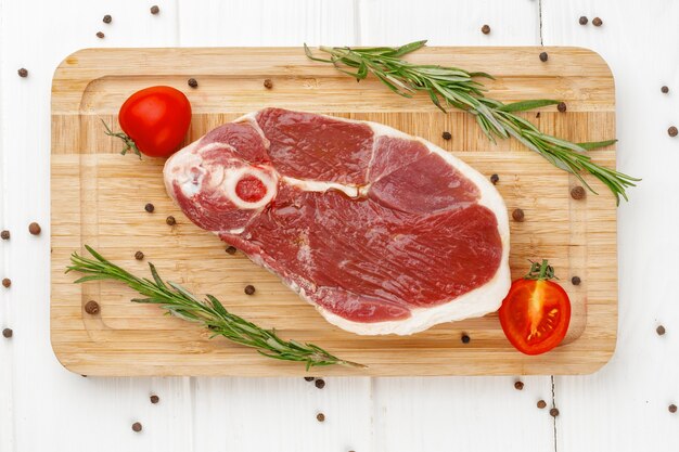 Rohes Lammsteak an Bord auf weißem Holztisch