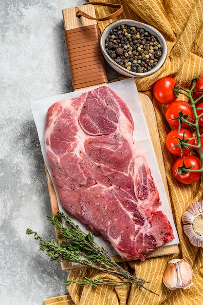 Rohes Marmorschweinefleischsteak auf einem hölzernen Schneidebrett.