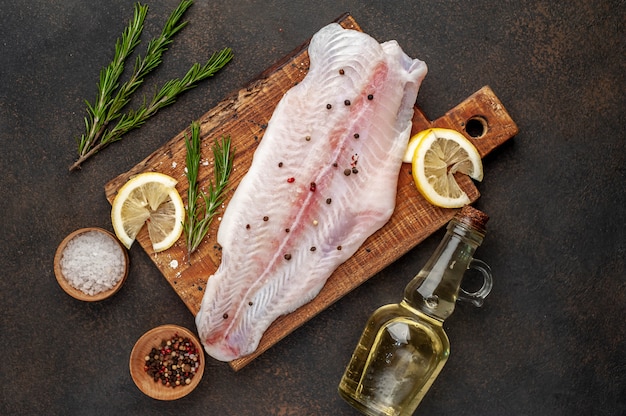 rohes Pangasiusfilet auf einem Schneidebrett mit Zitrone, Öl und Gewürzen. roher Fisch.