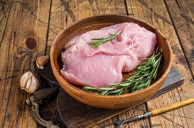 Rohes Putenbrustfilet, Geflügelfleisch in einem Holzteller. Holztisch. Draufsicht.