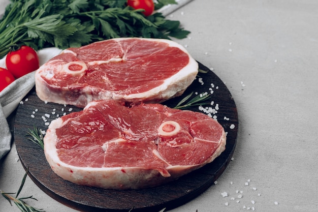 Rohes Rib-Eye-Rindersteak auf Holzschneidebrett auf grauer Nahaufnahme