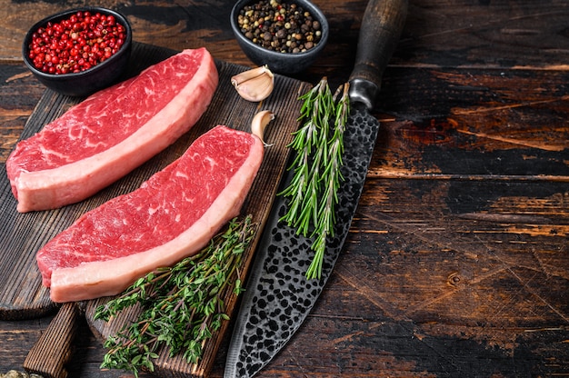 Rohes Rinderfilet-Fleischsteak auf einem schneidenden Holzbrett auf Holztisch. Draufsicht.