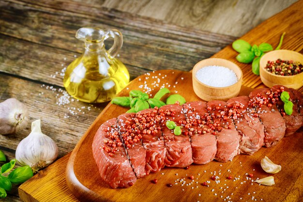 Rohes Rinderfilet mit Kräutern und Salz über Holzbrett.