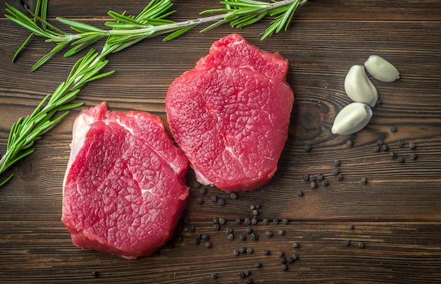 rohes Rinderfiletsteak mit Knoblauch und Pfeffer auf Holztisch