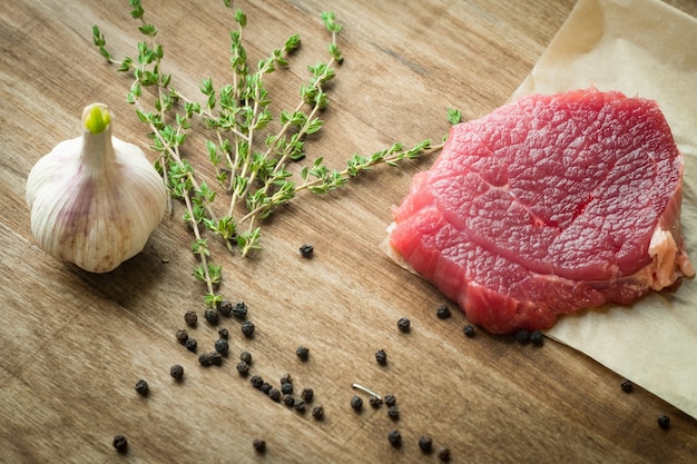 rohes Rinderfiletsteak mit Knoblauch und Thymian auf Holztisch