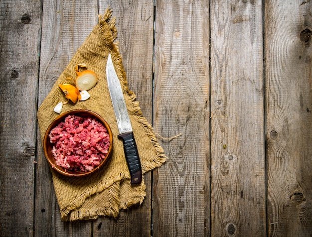 Rohes Rinderhackfleisch mit einem Fleischermesser und einer Zwiebel