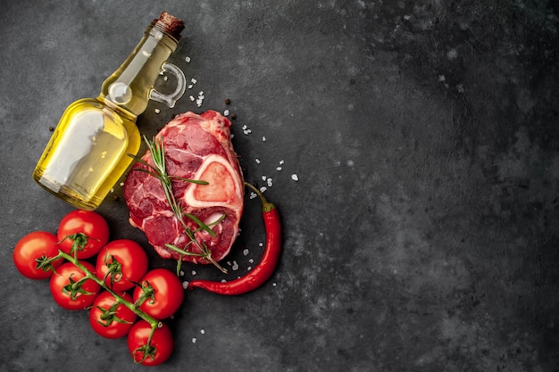 rohes Rindersteak mit Knochen und Gewürzen auf einem Steinhintergrund mit Kopierraum für Ihren Text