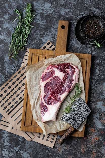 Rohes Rindersteak mit Rosmarin auf einem dunklen Holztisch