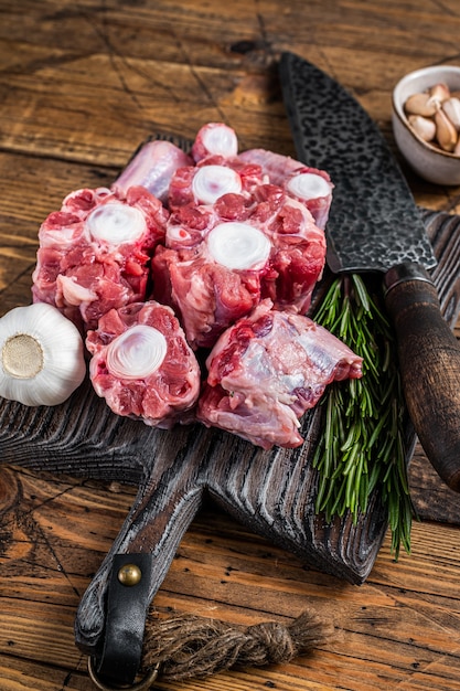 Rohes Rindfleisch Ochsenschwanz geschnittenes Fleisch auf Holzbrett mit Messer. hölzerner Hintergrund. Ansicht von oben.