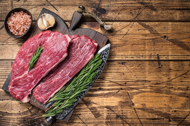 Rohes Rump Cap Steak oder Picanha Steak auf Holzbrett mit Metzgermesser. Holztisch. Draufsicht.