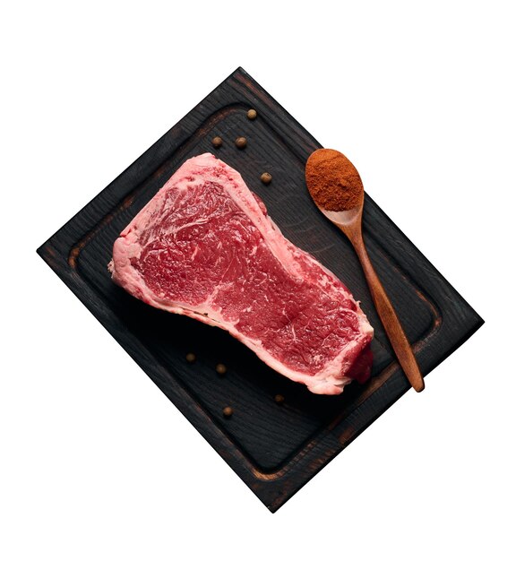 Rohes saftiges Stück Rindfleisch am Knochen liegt auf einem Holzschneidebrett Gewürze zum Kochen auf schwarzem Hintergrund Fleischfilet New York
