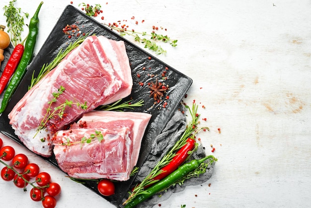Rohes Schweinebrust mit Zutaten und Gewürzen auf Küchenhintergrund Fleisch Draufsicht Rustikaler Stil