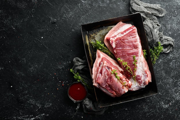 Rohes Schweinebrust mit Zutaten und Gewürzen auf Küchenhintergrund Fleisch Draufsicht Rustikaler Stil