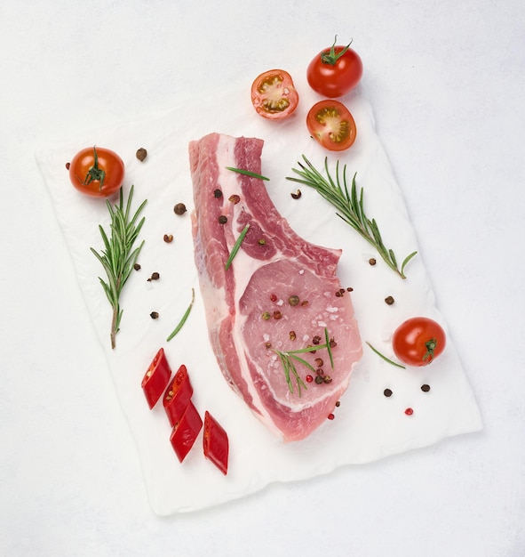 Rohes Schweinefilet mit Knochen und Gewürzen auf weißem Hintergrund Portion zum Mittag- und Abendessen Draufsicht