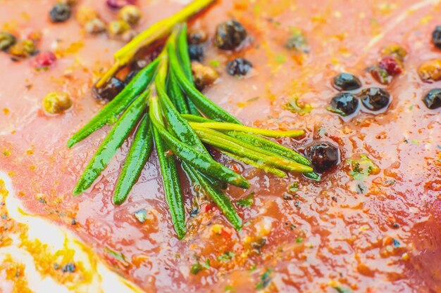 Rohes Schweinefleisch mit Gewürzen und grünem Rosmarinkraut Rotes Fleisch Textur Hintergrund Rohschinken Makrofoto Fett Frisches saftiges Steak