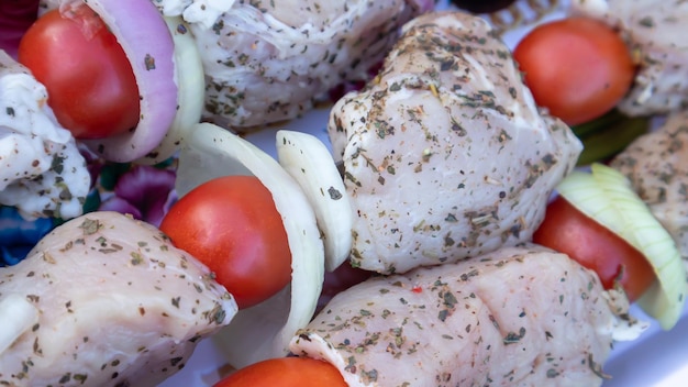 Rohes Schweinefleisch Schaschlik mit Gewürzen, Kirschtomaten und Zwiebeln am Spieß kochfertig. Frischer roher Kebab.