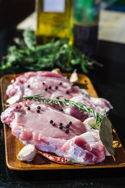 Rohes Schweinefleischsteak bereit zum Kochen mit Paprikas und Rosmarin