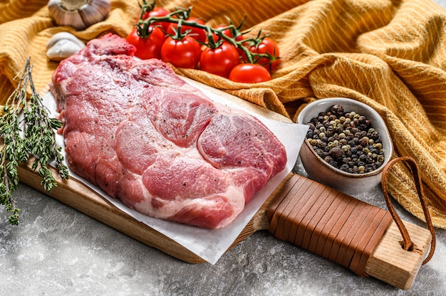 Rohes Schweinefleischsteak in der Nähe von Gewürzen und Kräutern