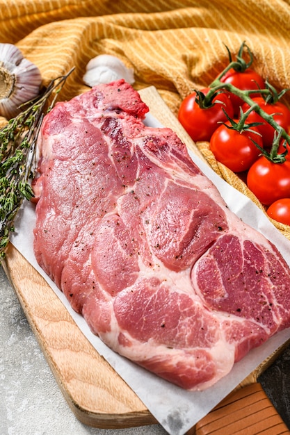 Rohes Schweinefleischsteak nahe Gewürzen und Tomaten