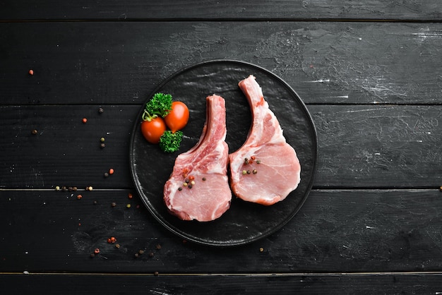 Rohes Schweinesteak mit Knochen Auf einem Teller mit Gewürzen und Kräutern Draufsicht Freier Platz für Ihren Text