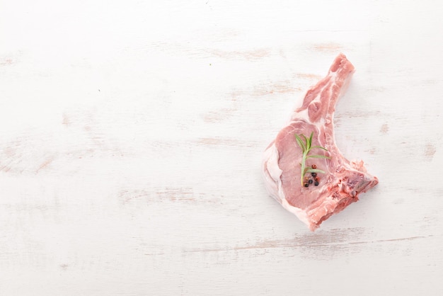 Rohes Steak am Knochen mit Gewürzen und Gemüse auf einem hölzernen Hintergrund Draufsicht Kopierbereich