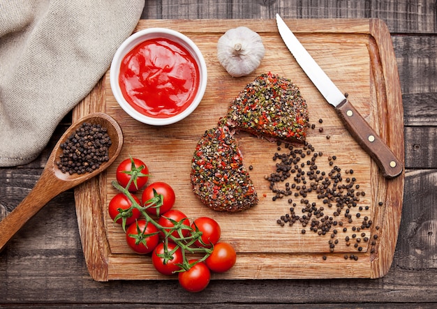 Rohes Steak des Rindfleisches mit Pfeffer und Tomaten auf hölzernem Brett