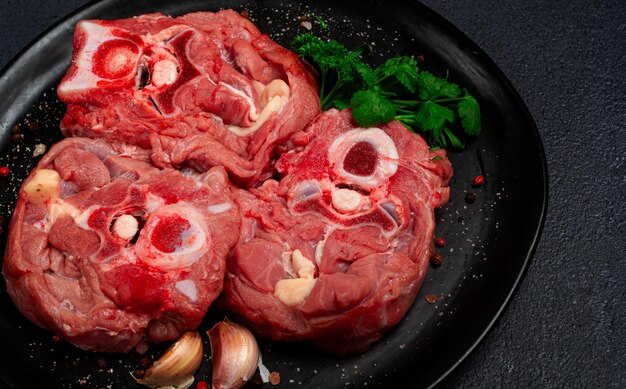 Foto rohes steak kalb hals auf dem knochen frisches fleisch auf einem schwarzen teller top view keine menschen