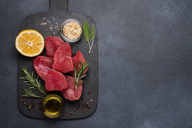 Rohes Thunfischsteak auf Schneidebrett mit Zutaten zum Kochen