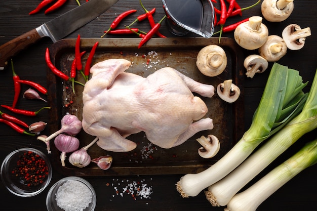 Rohes ungekochtes Huhn mit Bestandteilen für das Kochen