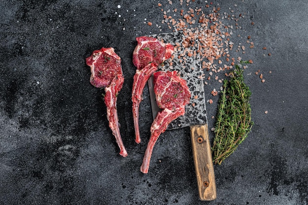 Rohes ungekochtes Lamm Hammelfleisch hackt Steaks auf einem Metzgererbeil. Schwarzer Hintergrund. Ansicht von oben.