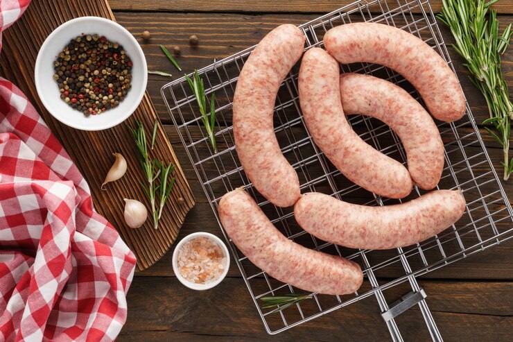 Rohwürste auf dem Grill und Zutaten zum Kochen.