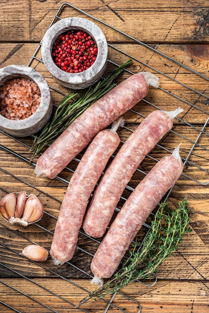 Rohwürste - Bratwurst mit Schweinefleisch auf einem Griil. Hölzerner Hintergrund. Ansicht von oben.