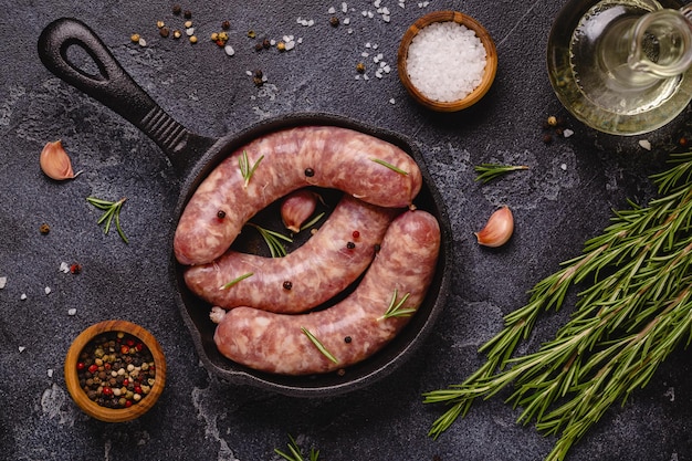 Rohwürste und Zutaten zum Kochen auf einem schwarzen Steintisch