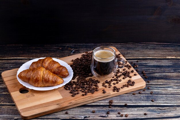 roissants com uma xícara de café em uma placa de madeira.