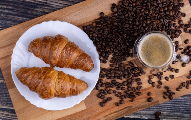 Roissants mit einer Tasse Kaffee auf einem Holzbrett.