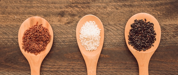 Foto rojo; arroz blanco y negro en una cuchara sobre fondo de madera