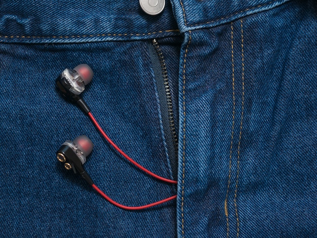 Rojo con auriculares negros sobresaliendo de sus pantalones vaqueros azules. Estilo juvenil de moda.