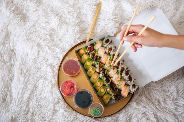 Role na mão da menina no contexto de uma bandeja com sushi.