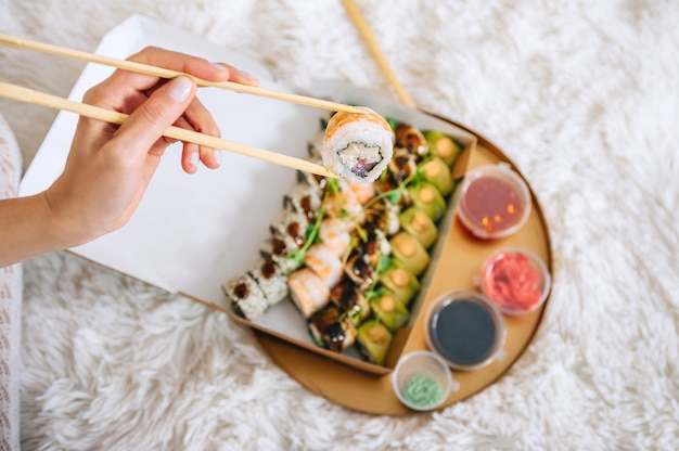 Role na mão da menina no contexto de uma bandeja com sushi.