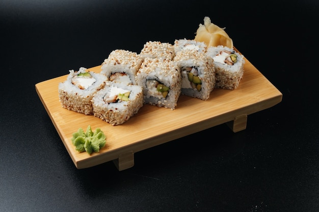 Role sushi tradicional com enguia e abacate na tábua de madeira