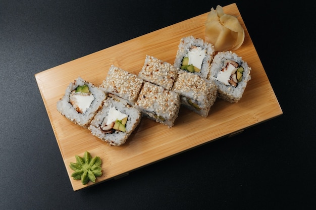 Role sushi tradicional com enguia e abacate na tábua de madeira