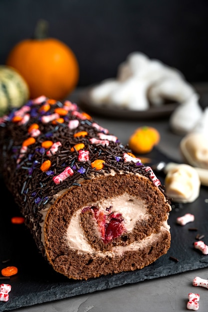 Rolinho de bolo de chocolate com creme e cerejas decoradas com rebuçados de açúcar para o dia das bruxas