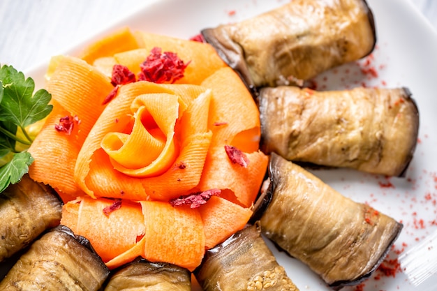 Rolinhos de berinjela com queijo e cenoura como rosa em chapa branca