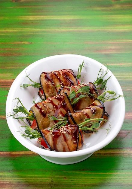 Rolinhos de legumes de berinjela com molho unagi Sobre fundo colorido de madeira Prato vegetariano