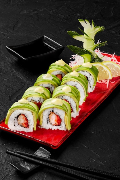 Rolinhos de sushi com camarão tobiko abacate e maionese servidos com pepino daikon ralado limão e...