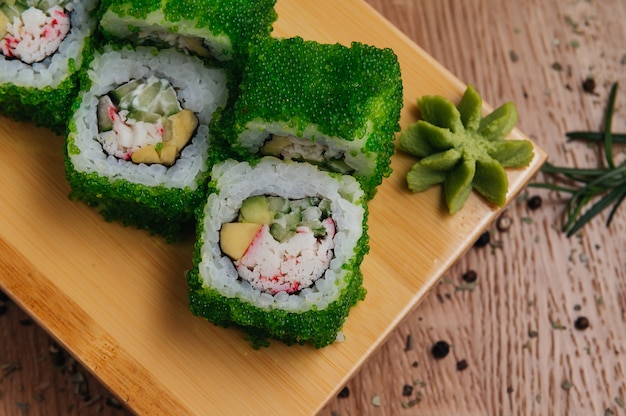 Rolinhos de Sushi com Caviar Tobiko Green na tábua de madeira