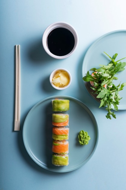 Rolinhos de sushi japonês com abacate e salmão, em estilo minimalista moderno. sobre um fundo azul com sombras sólidas